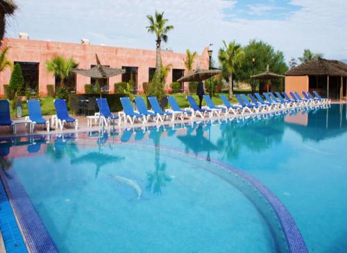 una gran piscina con sillas y sombrillas en Hôtel Jnane Ain Asserdoune, en Oulad Yaïch