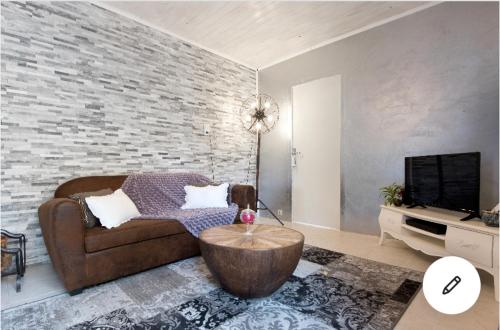 - un salon avec un canapé et un mur en briques dans l'établissement MAISON CHATEAU D'OLERON, au Château-dʼOléron