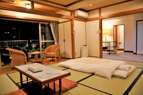 a bedroom with a bed and a table and a balcony at 川内ホテル in Satsumasendai
