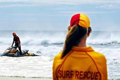 a woman sitting on the beach watching a man on a surfboard in the ocean at 13 Cypress Lane in Woorim