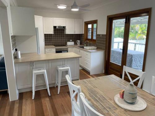 a kitchen with white cabinets and a table and chairs at 13 Cypress Lane in Woorim