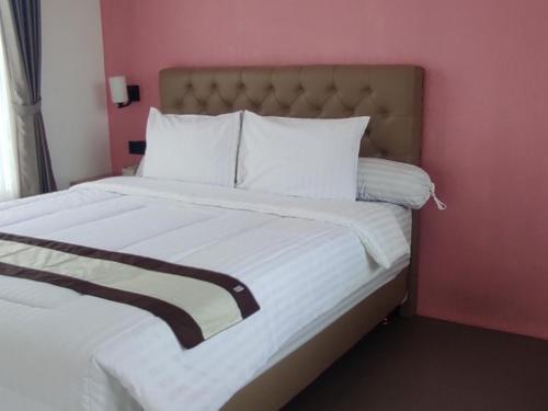 uma cama num quarto com uma parede rosa em Aliandra Villa by The Lavana em Yogyakarta