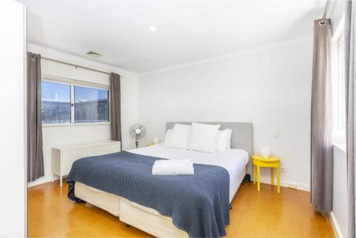 a white bedroom with a large bed and a window at Cottesloe Azura Apartment in Perth