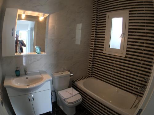 een badkamer met een wastafel, een toilet en een bad bij Xenos Villa 3 - Luxury Villa With Private Pool Near The Sea. in Tigaki