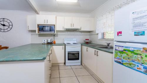 a kitchen with white cabinets and green counter tops at Comfy Ground Floor Unit opposite waterfront! Welsby Pde, Bongaree in Bellara