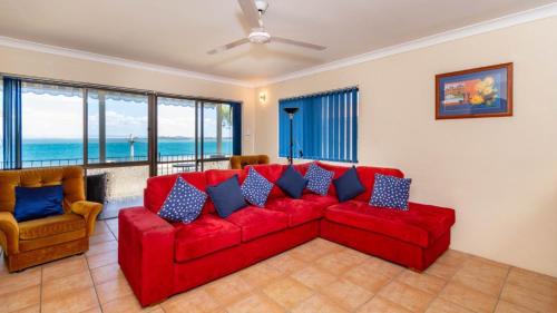 a living room with a red couch and chairs at Fantastic Views from this top floor unit! in Bongaree