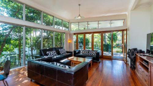 a living room with a leather couch and glass windows at Decked out for a Fantastic Holiday - Winnett St, Woorim (Upstairs only) in Woorim