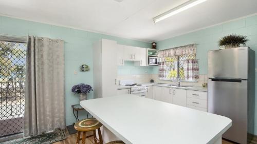 uma cozinha com um balcão branco e um frigorífico em First floor unit close to shops, park and waterfront! em Bongaree