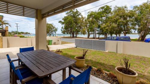 a patio with a wooden table and chairs on a porch at Stunning Waterfront Home with pool - Sylvan Beach Esp, Bellara in Bellara
