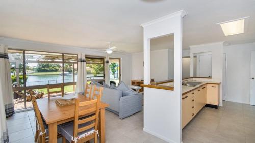a kitchen and living room with a table and a couch at Lowset home on the canal - Dolphin Dr, Bongaree in Bongaree