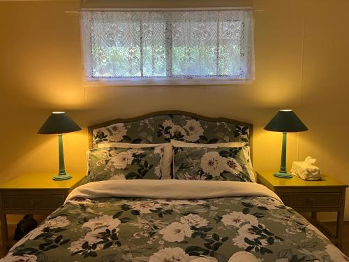 a bedroom with a bed with two lamps and a window at English Gardens - Forest Spa Suite in Springbrook