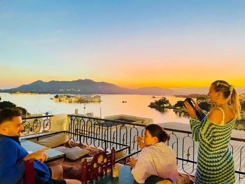 a group of people sitting on a balcony taking a picture of the sunset at Dreamyard Udaipur in Udaipur