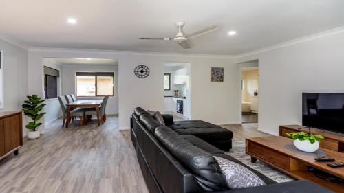 a living room with a leather couch and a table at Freshly revovated Dog Friendly House walking distance to Waterfront! in Bellara