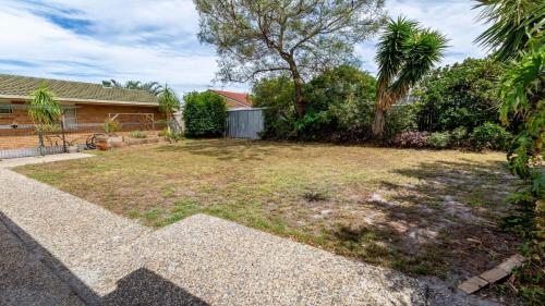a yard with a house and trees and a building at Freshly revovated Dog Friendly House walking distance to Waterfront! in Bellara