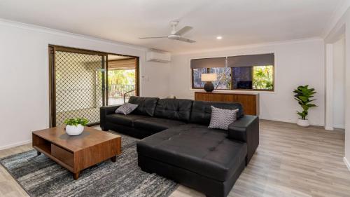 a living room with a black leather couch and a table at Freshly revovated Dog Friendly House walking distance to Waterfront! in Bellara