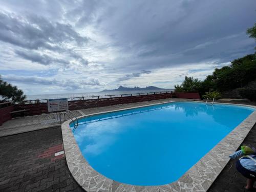 a large blue swimming pool with the ocean in the background at OLotus Studio Punaauia in Punaauia