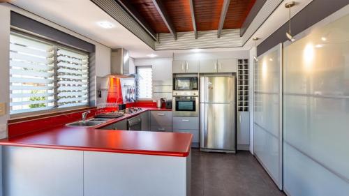 cocina con encimera roja y nevera en Unique Getaway 300m To Bribie Foreshore, Bongaree, en Bongaree