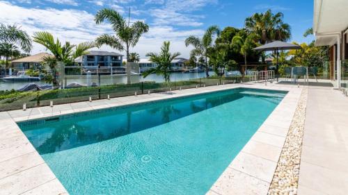 a swimming pool with blue water and palm trees at Paradise On The Promontory in Banksia Beach