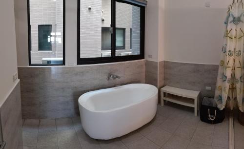 uma banheira branca na casa de banho com uma janela em 埔里包棟民宿木子小屋 em Puli