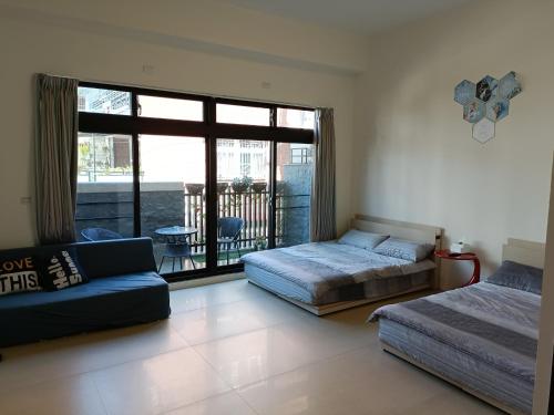 1 dormitorio con 2 camas, sofá y balcón en 埔里包棟民宿木子小屋, en Puli