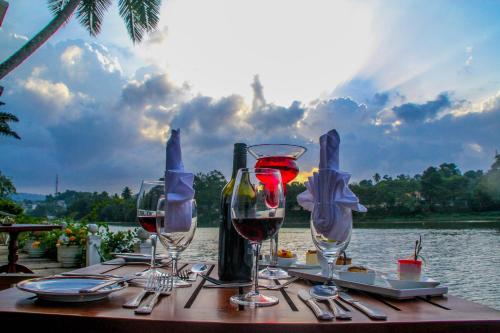 a table with wine glasses on a table near the water at Mahaweli Reach Hotel in Kandy