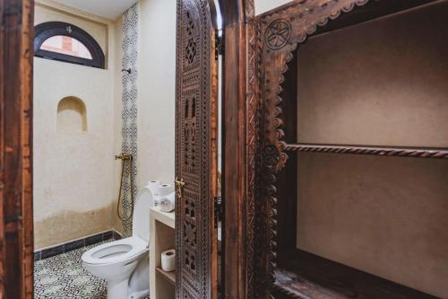 een badkamer met een toilet en een houten deur bij Auberge RIAD DLIM Tamraght in Tamraght Ouzdar