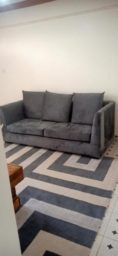 eine graue Couch in einem Wohnzimmer mit einem Teppich in der Unterkunft Zuri Stays Machakos Town in Machakos