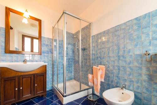 uma casa de banho em azulejos azuis com um lavatório e um chuveiro em Villa degli Orti em Acqualagna