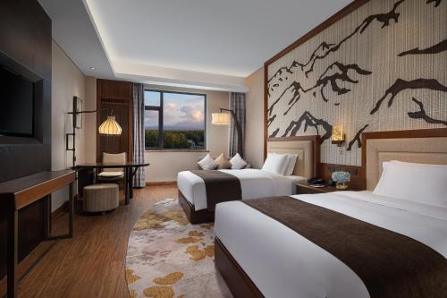 Crowne Plaza Resort Changbaishan Hot Spring, an IHG Hotel في Antu: غرفة فندقية بسريرين وتلفزيون بشاشة مسطحة