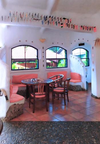 a room with a table and chairs and windows at Hotel La Hasienda in Kupang