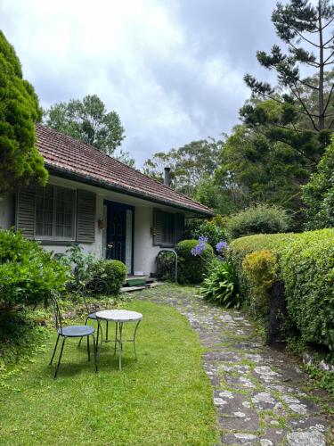 a house with two chairs and a table in the yard at English Gardens - Garden Retreat in Springbrook