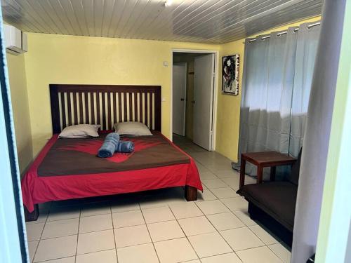 Fare Ninamu Maison individuel 2 chambres في بورا بورا: غرفة نوم بسرير وبطانية حمراء وكرسي