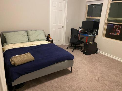 een slaapkamer met een bed en een bureau met een computer bij New home less than 5 minutes from Lackland Base private room in San Antonio