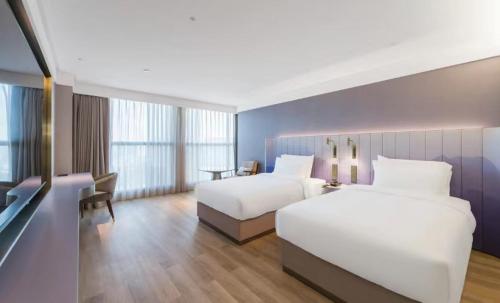 een hotelkamer met 2 bedden en een bureau bij Manxin Hotel Guangzhou Baiyun Airport Branch in Guangzhou