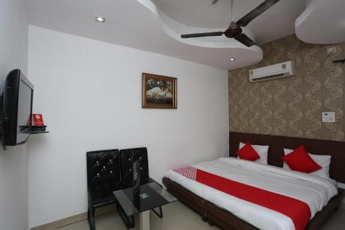een slaapkamer met een bed met rode kussens en een televisie bij Hotel Pearl in Karnal