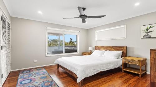 a white bedroom with a bed and a window at 1 Ilya Street Currimundi QLD in Kawana Waters