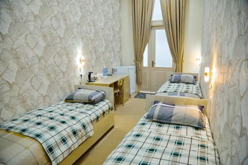 Cette chambre comprend 3 lits et un bureau. dans l'établissement YUKSALISH HOSTEL, à Samarcande