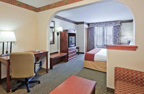 a hotel room with a bedroom with a bed and a desk at Holiday Inn Express Hotel & Suites Forest, an IHG Hotel in Forest