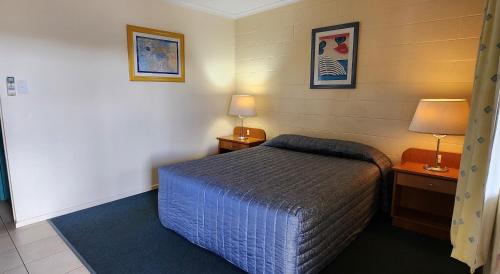 a small bedroom with a bed and two lamps at Nanango Antler Motel in Nanango