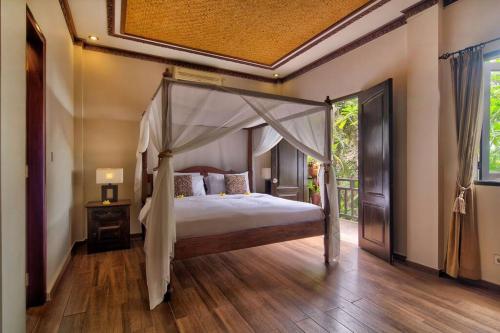 a bedroom with a canopy bed and a wooden floor at Uluwatu Huge 6 Bed Spa Villa - G8 views & Child Friendly in Jimbaran