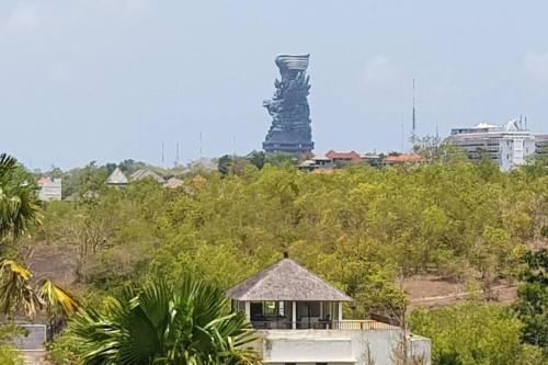 a building with a tower in the background with trees at Uluwatu Huge 6 Bed Spa Villa - G8 views & Child Friendly in Jimbaran