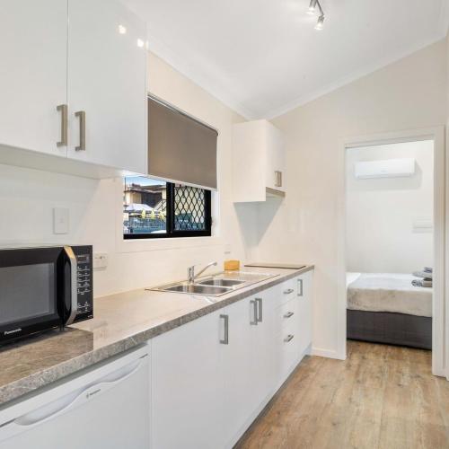 a white kitchen with a sink and a microwave at Kenilworth Country Cabins in Kenilworth