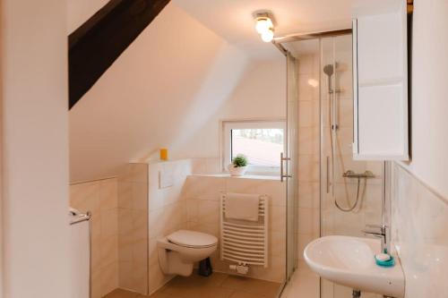 Baño blanco con aseo y lavamanos en Ländlicher Rückzugsort: Entspanne dich hier, en Hatten