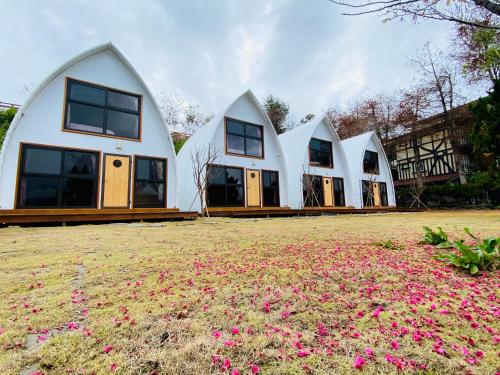 una fila di case bianche con fiori rosa in un campo di 見晴花園山莊Sunshine Villa a Ren'ai