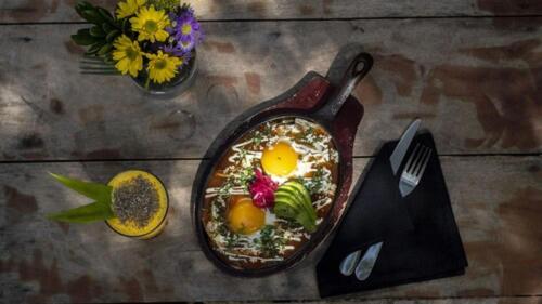 a table with a pan of food and a fork and flowers at Una Vida in Tulum