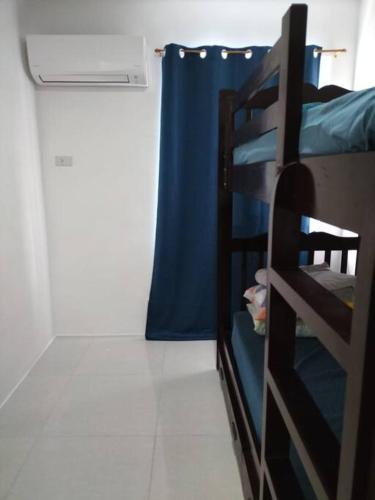 a bunk bed in a room with a blue curtain at House in Philippines in Liloan