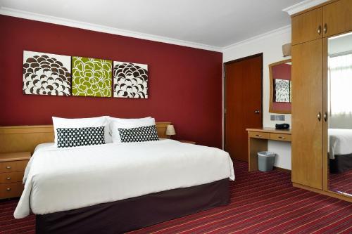 a hotel room with a large bed and a red wall at The Assembly Place at Stevens, Service Residences in Singapore