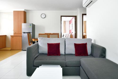 a living room with a gray couch with two red pillows at The Assembly Place at Stevens, Service Residences in Singapore