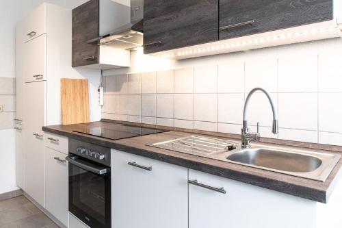 a kitchen with white cabinets and a sink at Villa Elbblick mit Garten in Tangermünde