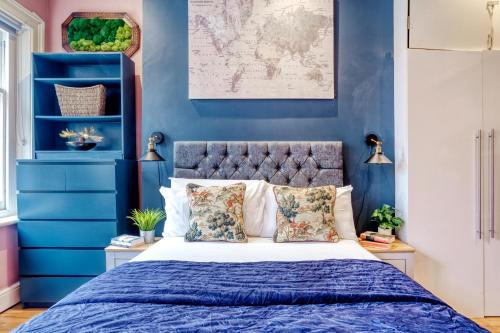 Schlafzimmer mit blauen Wänden und einem Bett mit Kissen in der Unterkunft Sunny Corner Apartment in Center of London in London